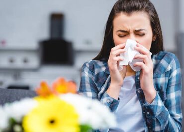 A woman blowing her nose due to allergies